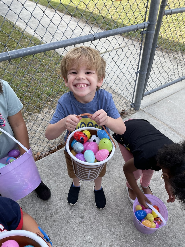 A little boy is showing off all of the eggs he found during his Easter egg hunt.