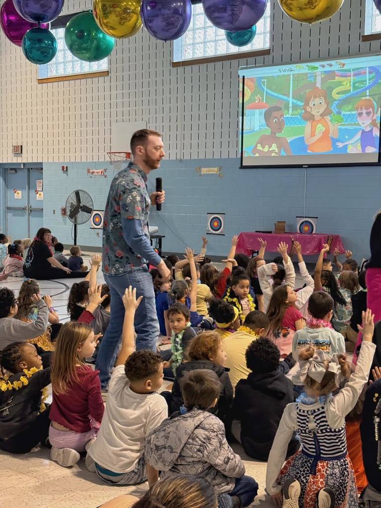 David Gorman speaking to kids and some kids have their hands raised.