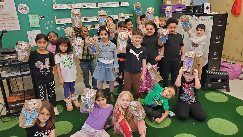 Students holding puppets they made of Barack Obama. 