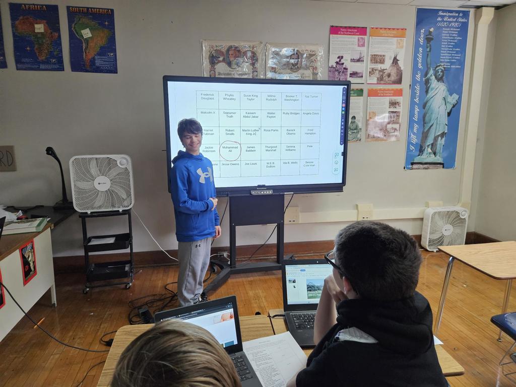A student standing in front of a large screen and are ready to present. 