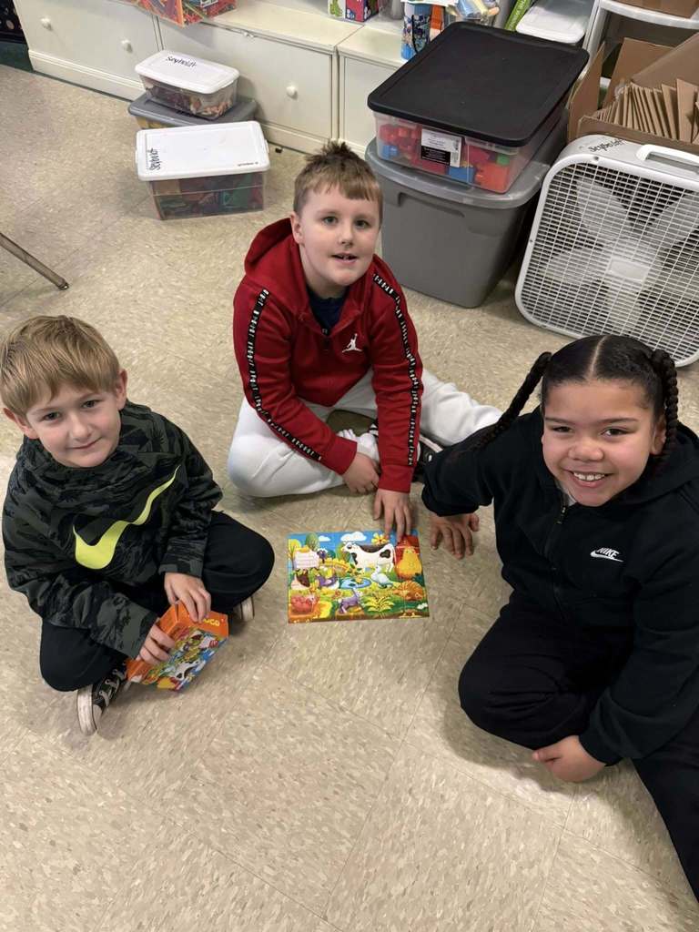 Students are putting together a puzzle on the floor. 
