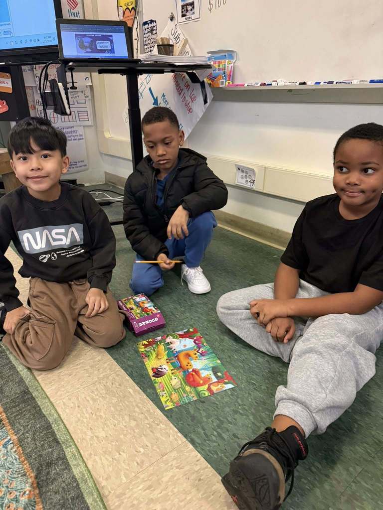 Students are putting together a puzzle on the floor. 