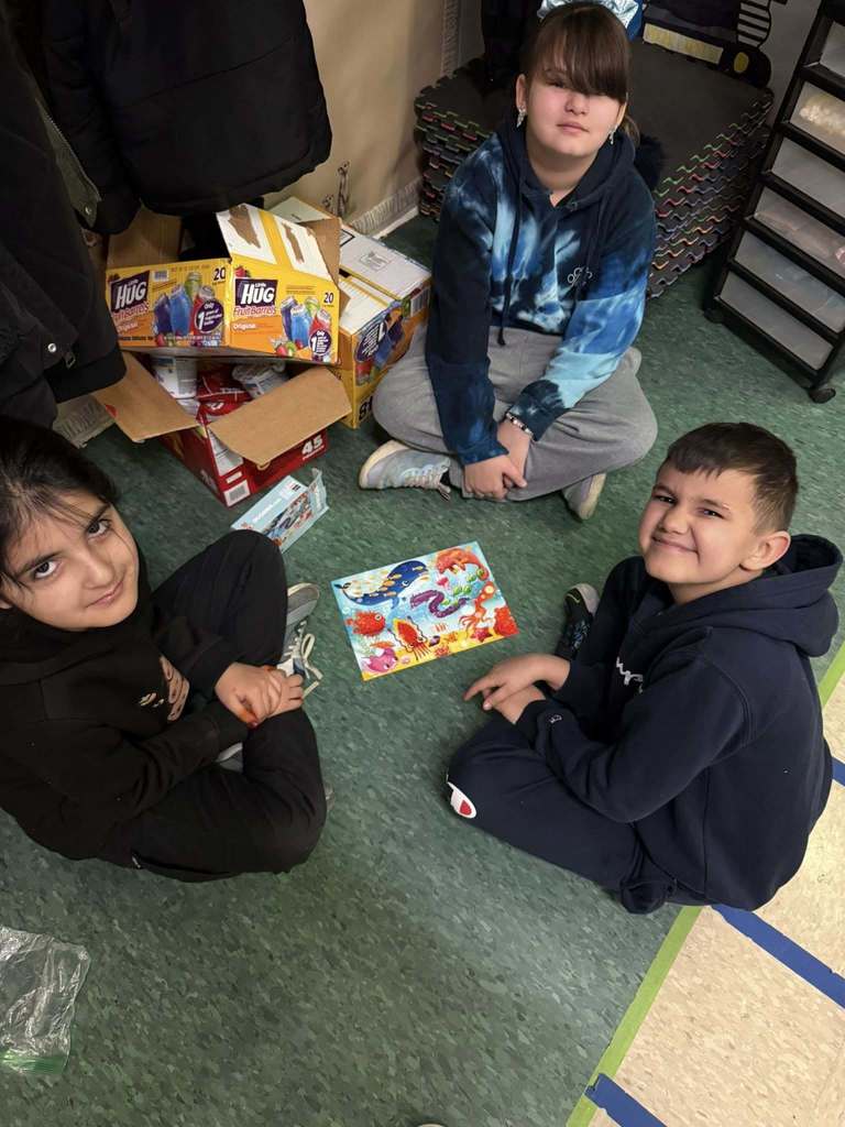 Students are putting together a puzzle on the floor. 