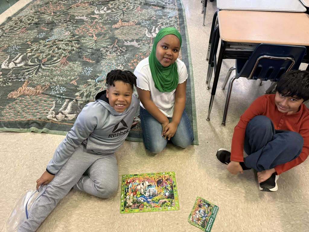 Students are putting together a puzzle on the floor. 