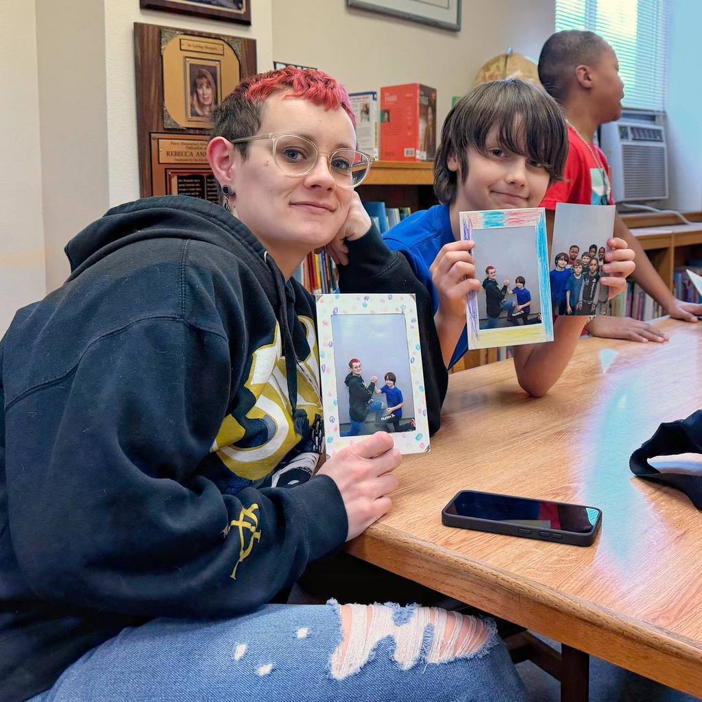 An adult and student showing the frames the decorated with their photo inside. 