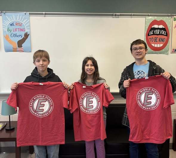 Students holding red shirts with the East Middle School logo on them. 