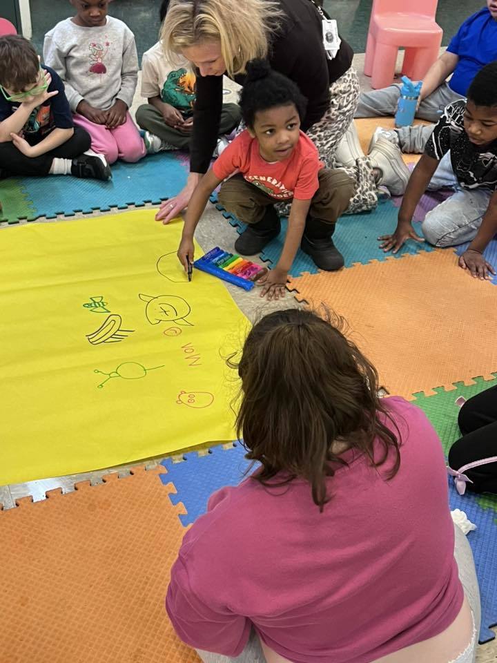 Students coloring on yellow paper.