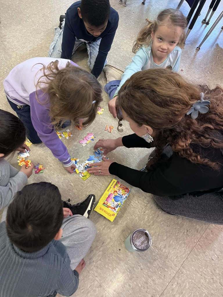 Students putting together a puzzle with an adults.