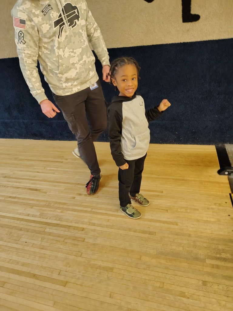 A child smiling at a bowling ally. 