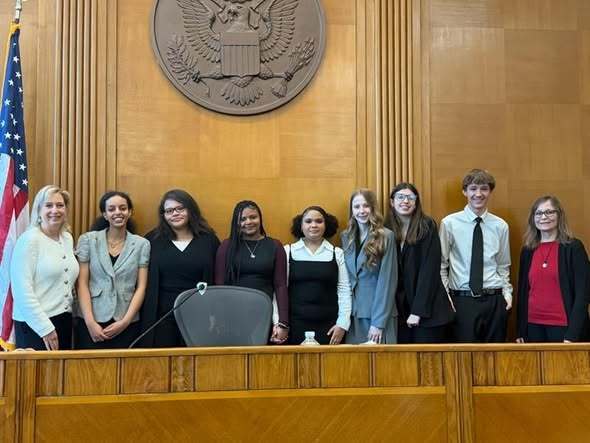 Group of students and adults in a courthouse.