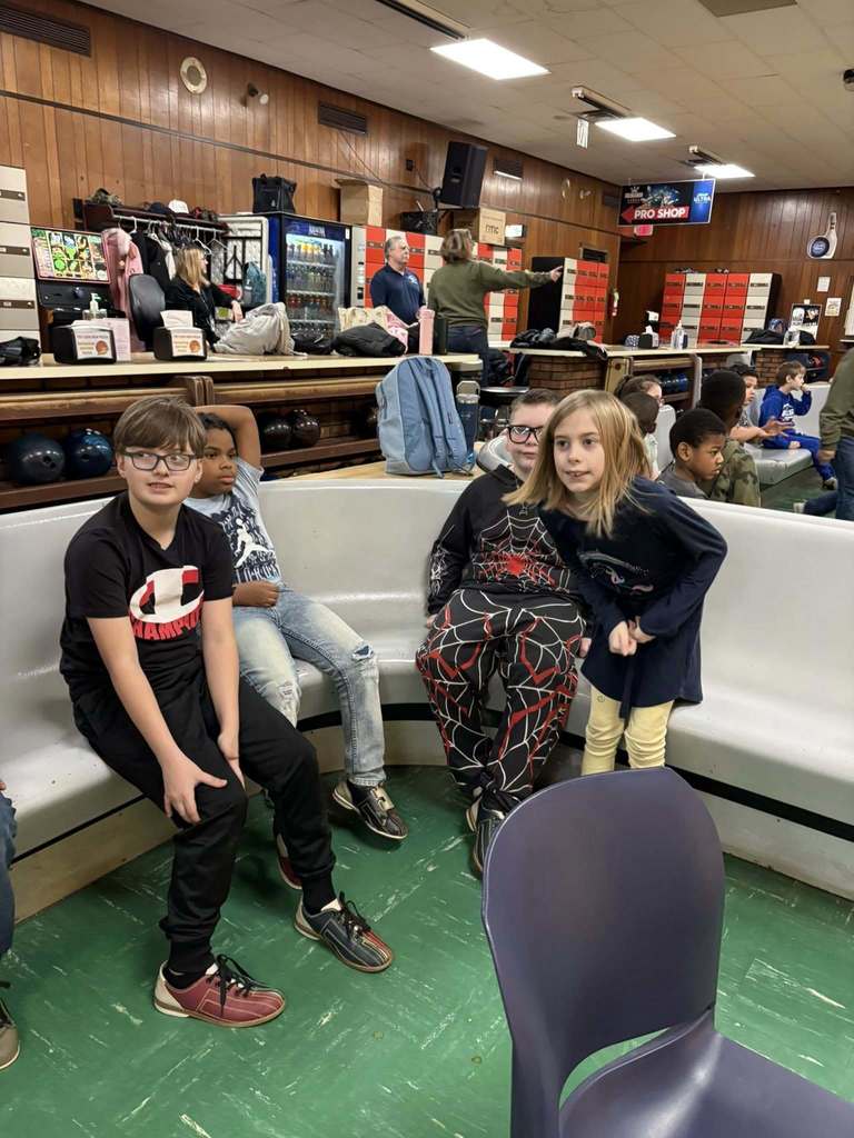 Kids sitting in a bowling ally. 