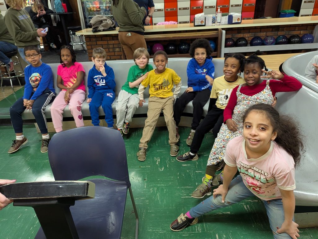 A group of students sitting in a bowling ally. 