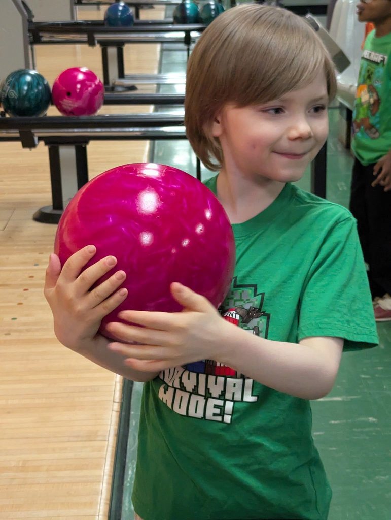 A kid holding a bowling ball.