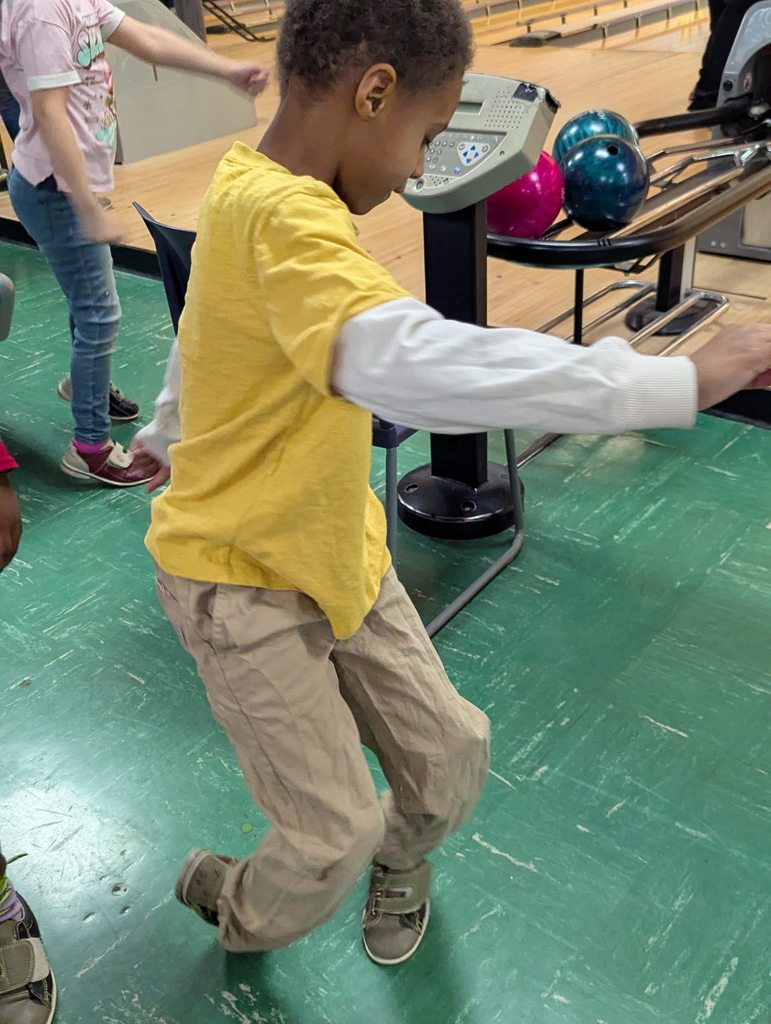 A kid dancing at a bowling ally.