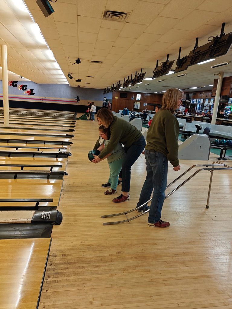 A teacher helping a student bowl. 