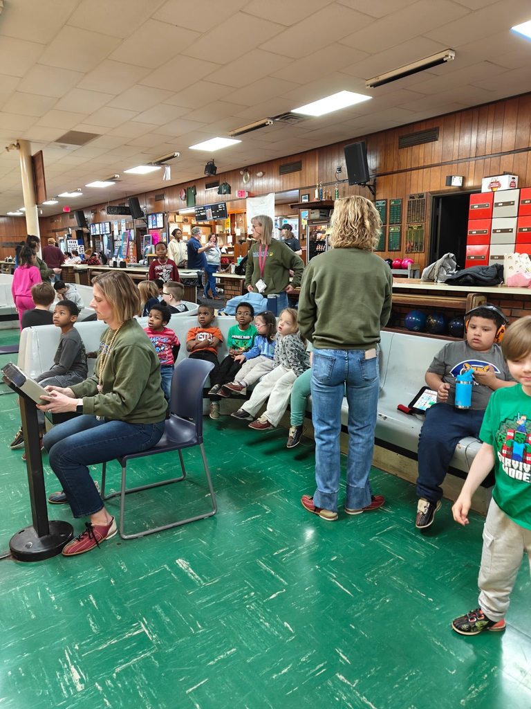 Kids sitting in a bowling ally.