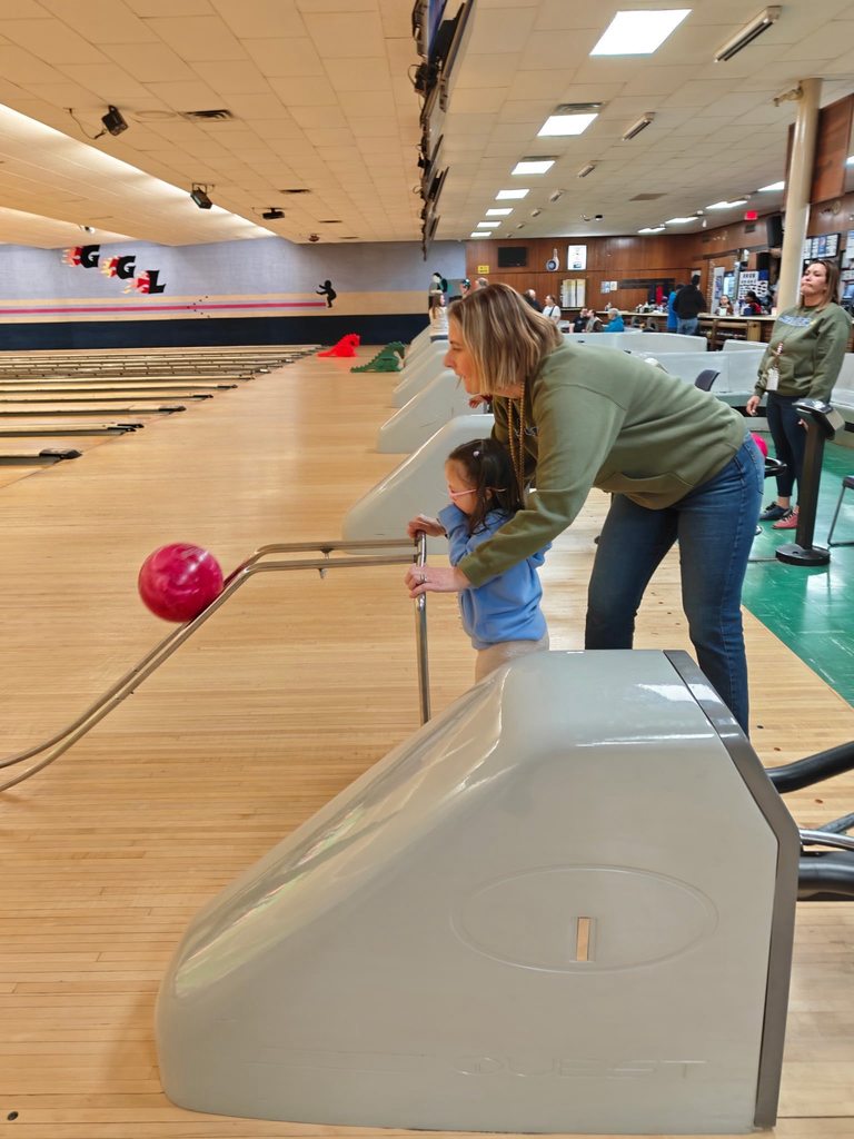 A teacher helping a student bowl. 