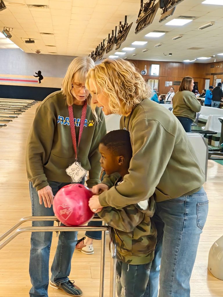 A teacher helping a student bowl. 