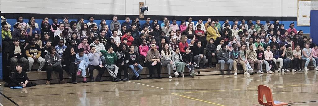 Students sitting on bleachers in the school gym. 