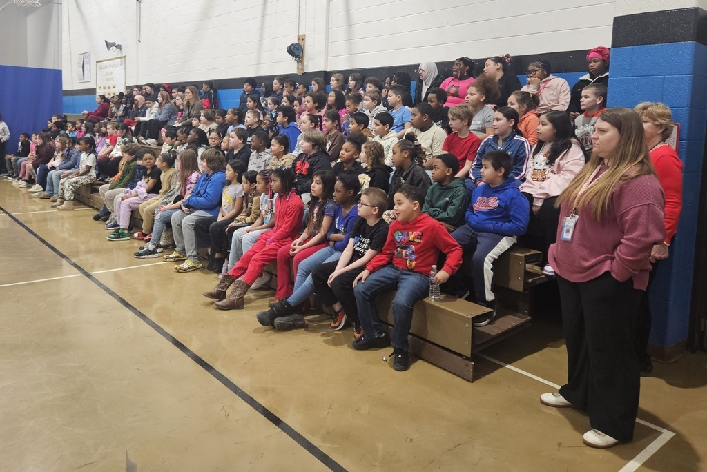 Students sitting on bleachers in the school gym. 