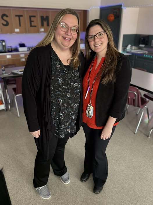 Two women standing in a classroom.