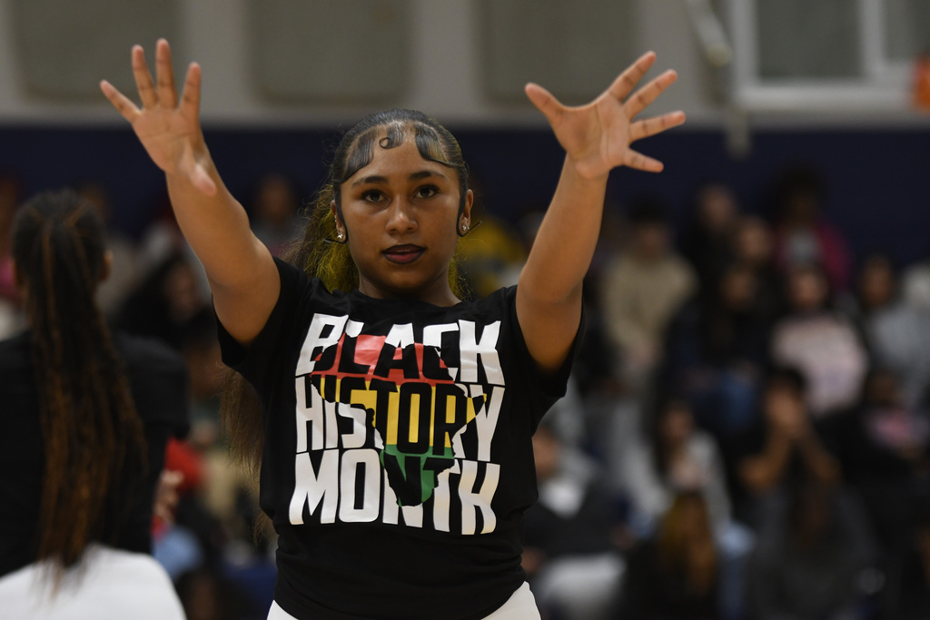 dancer with her arms extended out wearing a black history month shirt