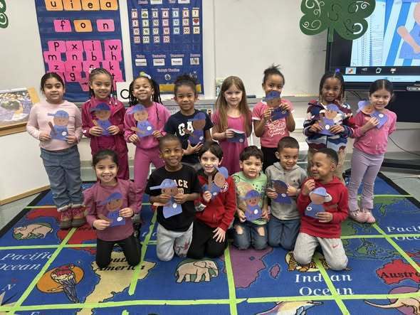 Students in a classroom holding their cut outs they made of Jackie Robinson. 