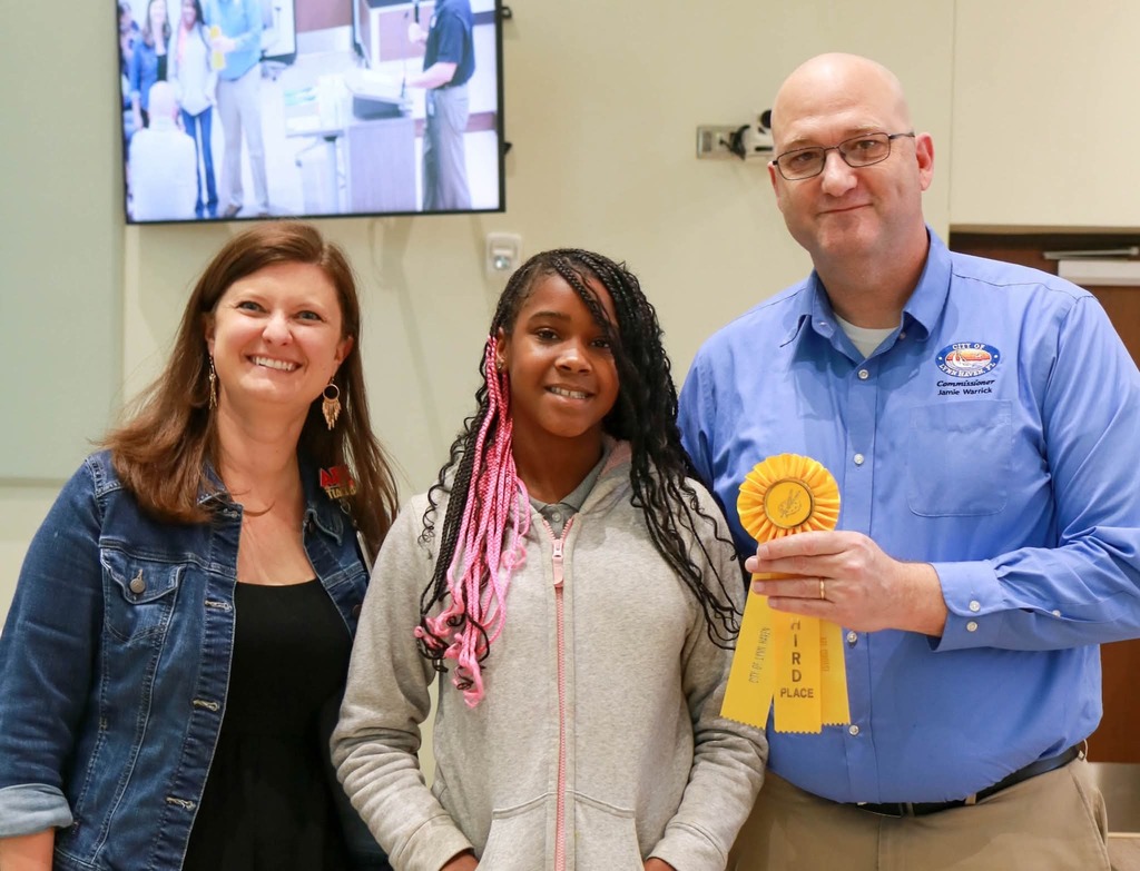Student poses with teacher and city official.