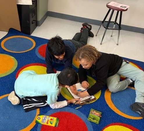Three children on floor, using crayons and coloring books. Bright, multicolored rug. White walls.