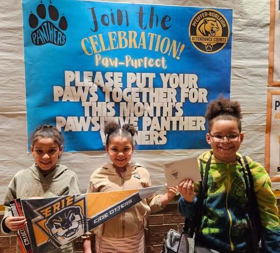 Students smiling and holding an Erie Otters banner. 