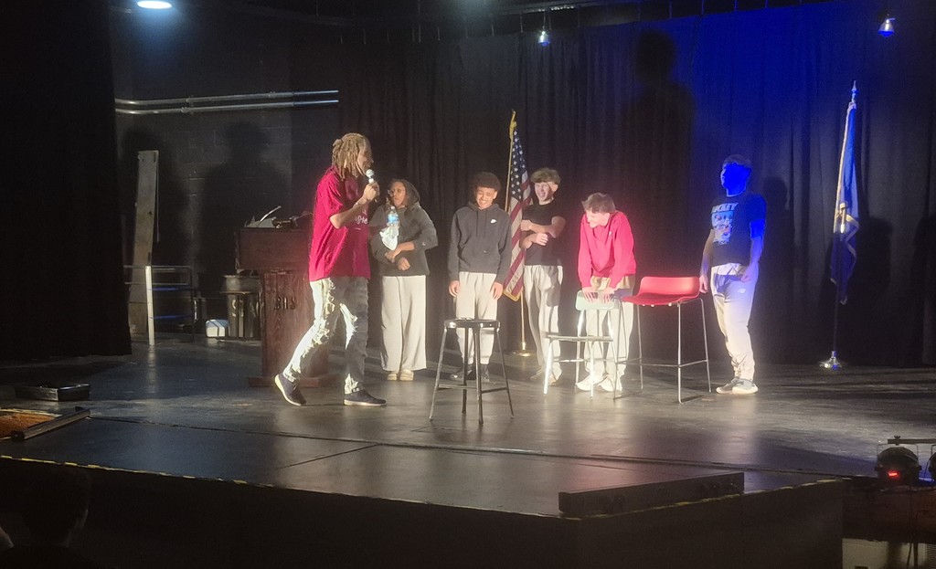 Comedian talking to students on stage. 
