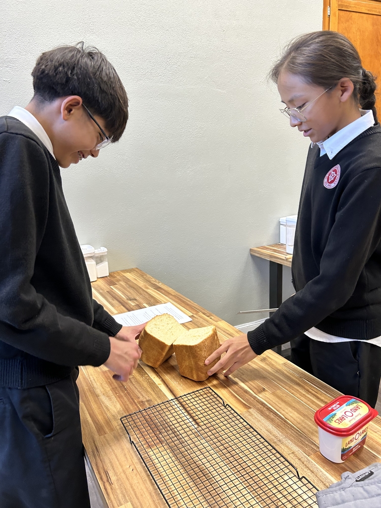 Two boys cutting a loaf of bread