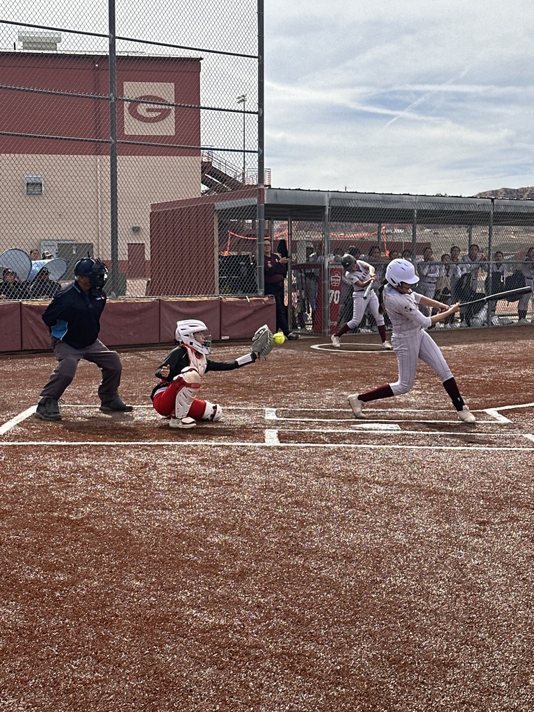 Girl swinging at softball at home plate 