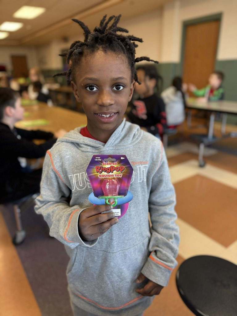 A kid holding a toy they won. 