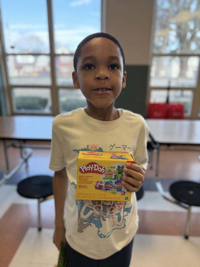 A kid holding Play-doh they won. 