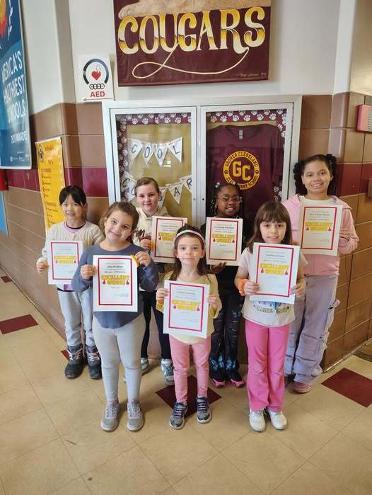 Students standing in a hall and holding their awards. 