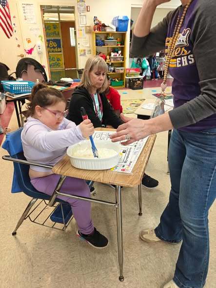 A teacher teaching students how to cook in class with hands on experience. 