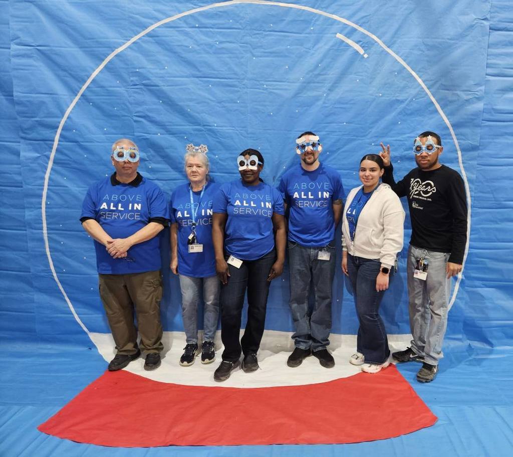 A group of people taking a photo in front of a snow globe backdrop. 