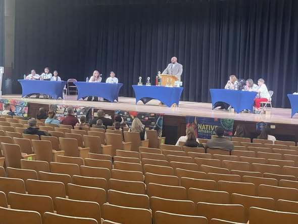 Students on stage and individuals sitting in the crowd during the multicultural quiz bowl. 