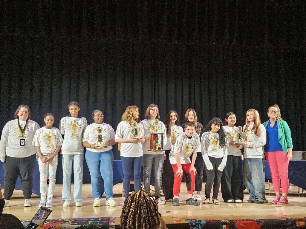 All the competitors standing together and holding their trophies at the multicultural quiz bowl.