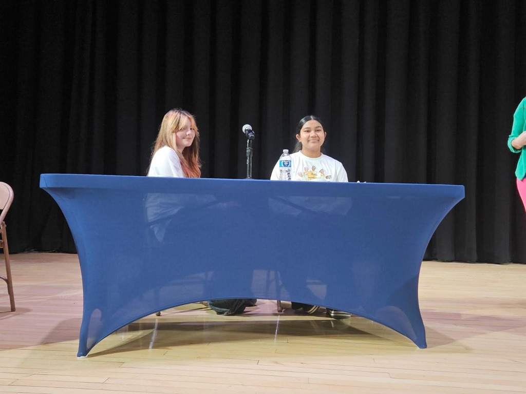 Two young ladies sitting behind a table at the multicultural quiz bowl.