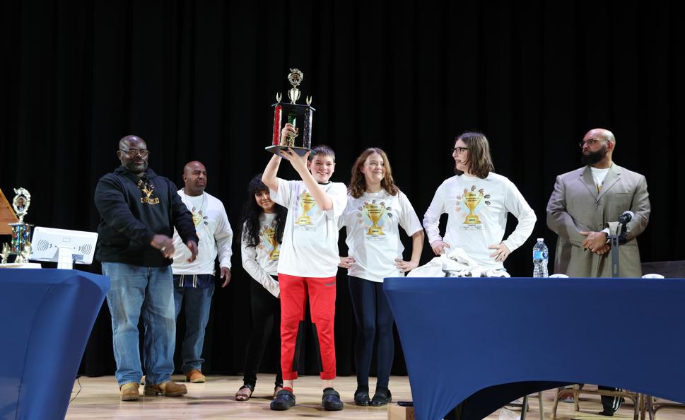 A student holding up the trophy him and his team won. 