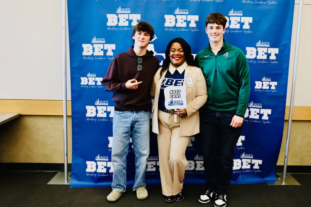 Two young men standing next to Dr. Natalyn Gibbs.