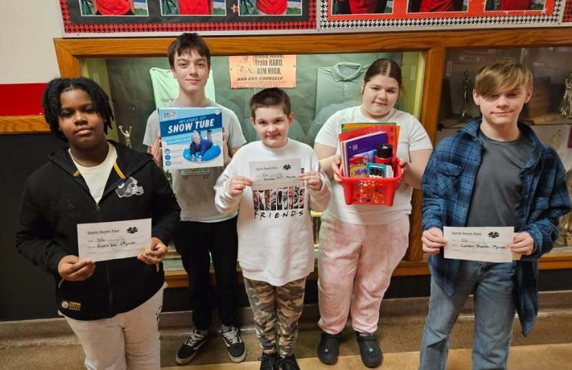 Students holding a fun basket, a box that has a snow tube in it and vouchers. 
