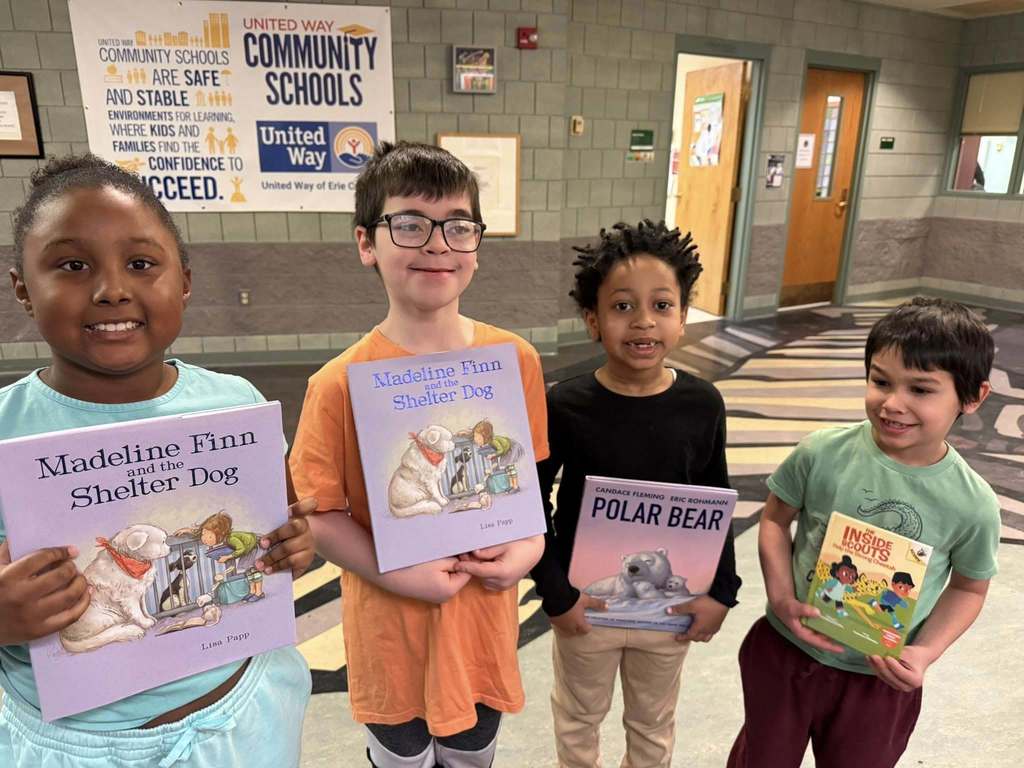 Students are holding books and smiling. 