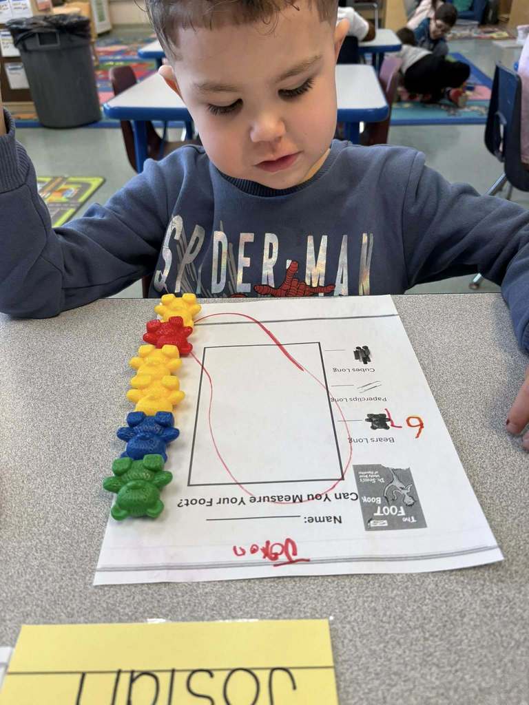 Student using colorful tog to count how big their drawing of their foot is. 