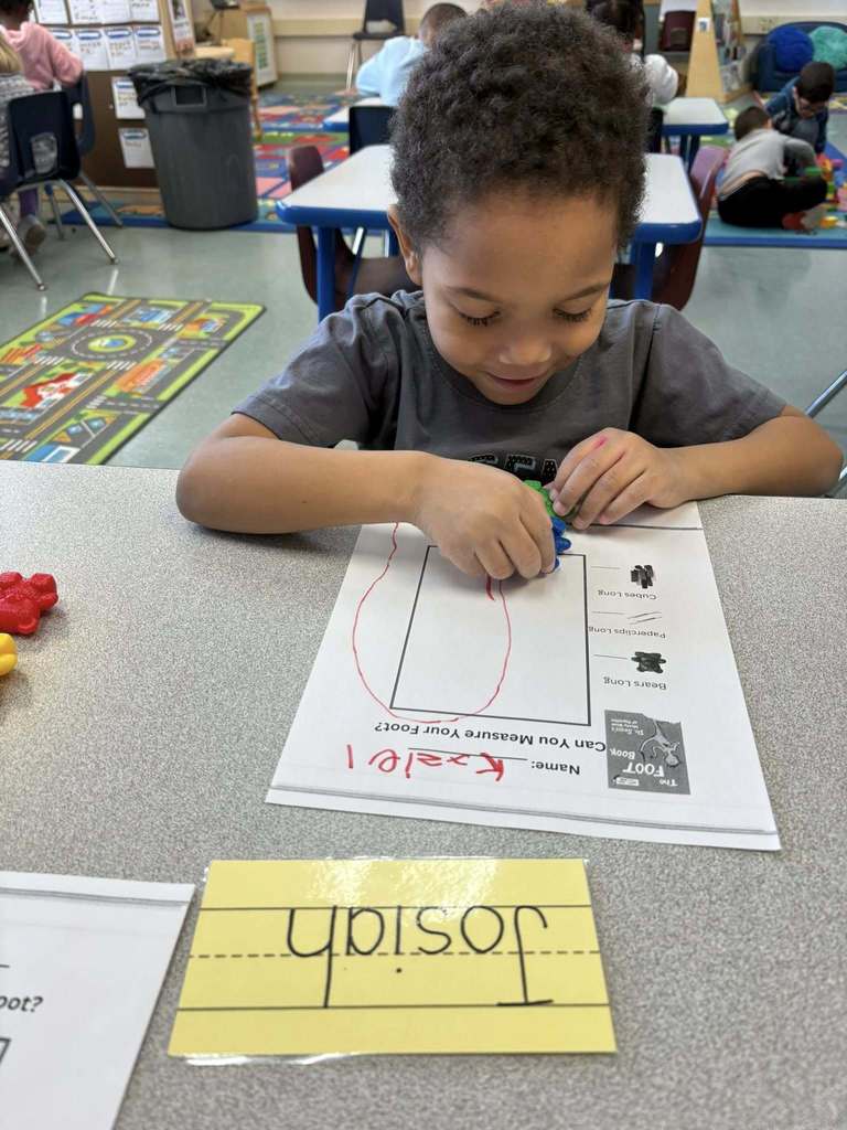 Student using colorful tog to count how big their drawing of their foot is. 