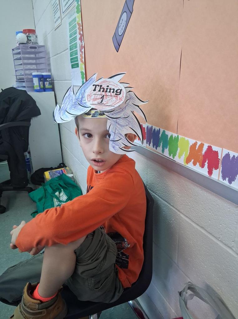 Student wearing an orange shirt and a paper cut out that says Thing 1 on it. 