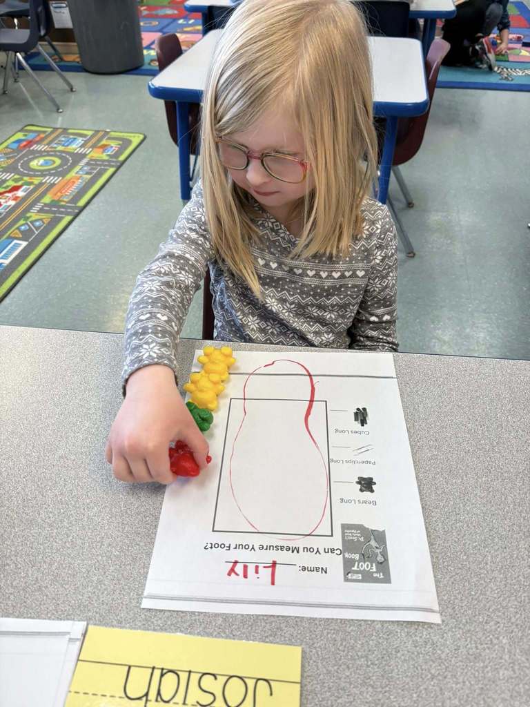 Student using colorful tog to count how big their drawing of their foot is. 