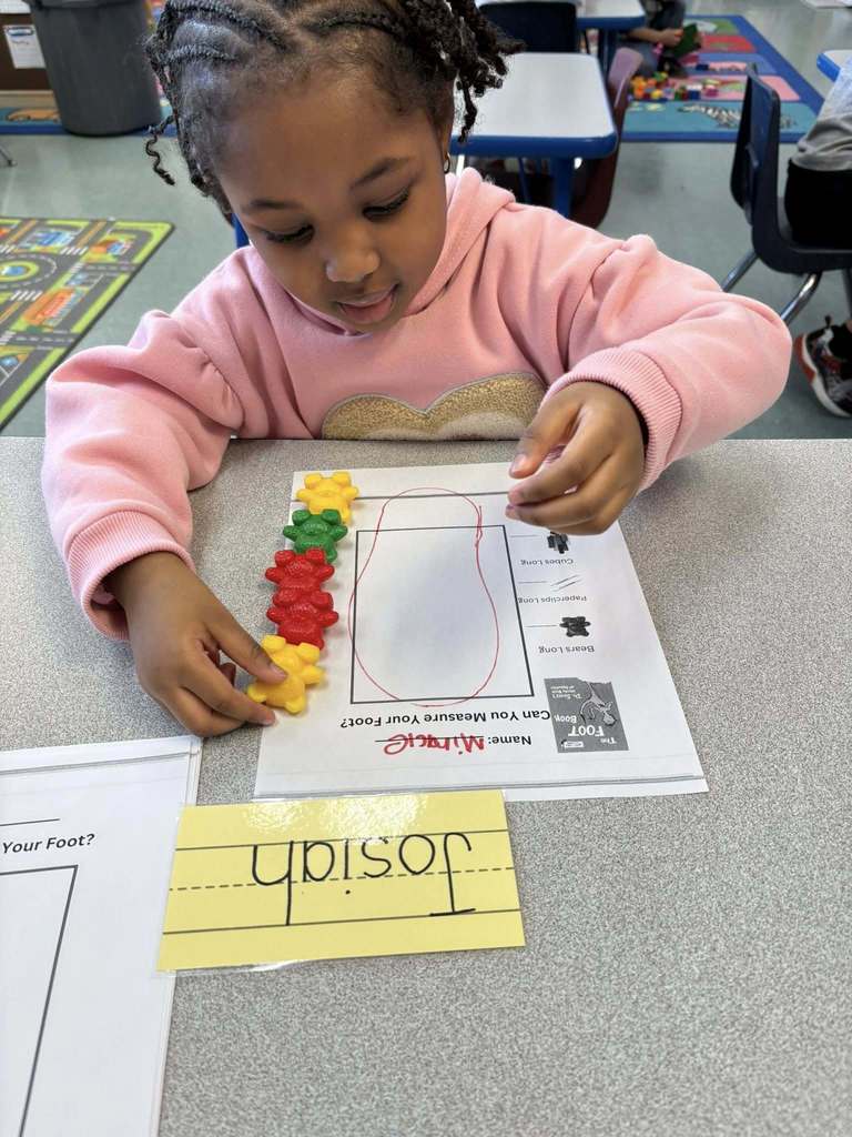 Student using colorful tog to count how big their drawing of their foot is. 